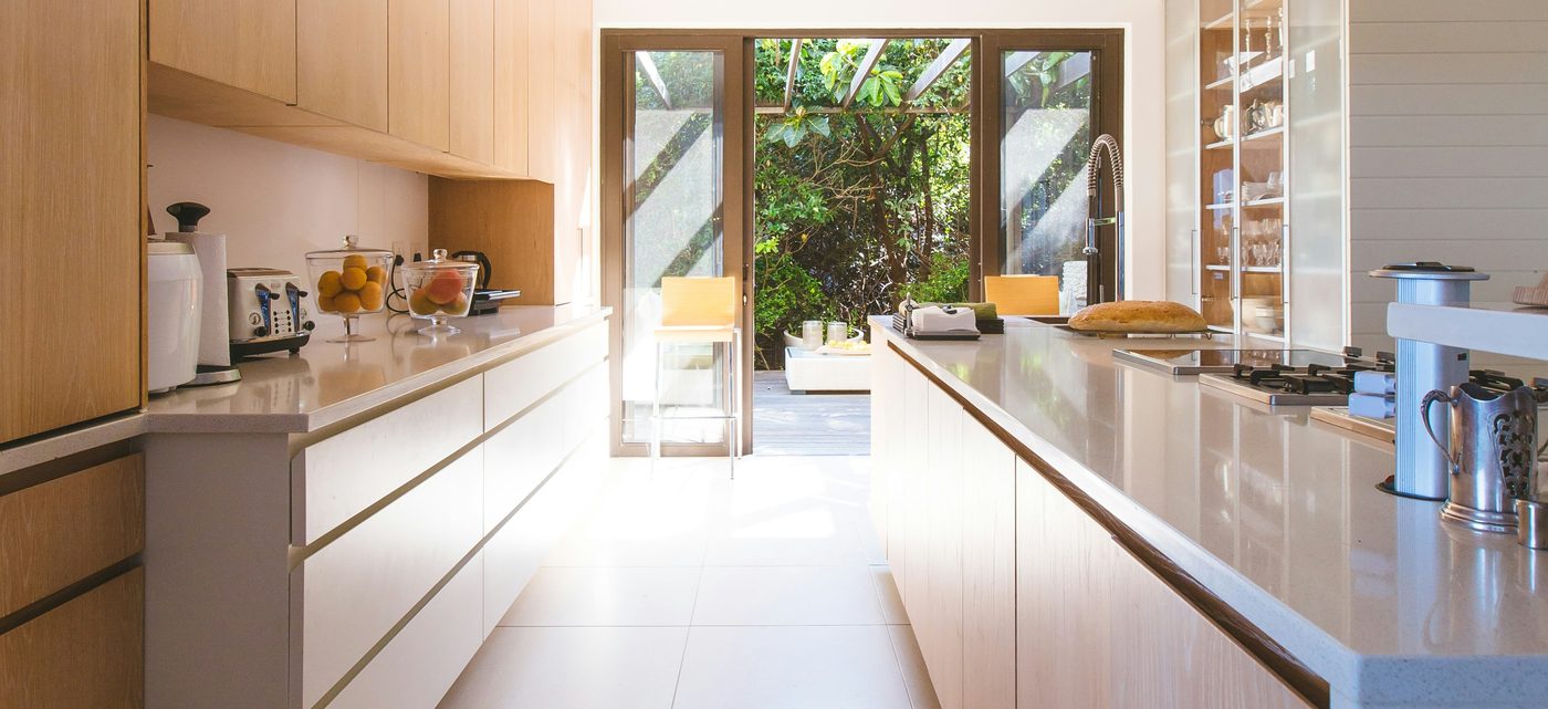 Helle, moderne Küche mit Holzfronten und großer Glastür zur Terrasse